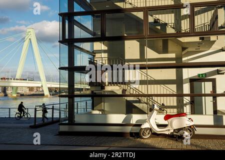 Eine Vespa steht vor der verglasten Treppe eines Kranhauses im Rheinauer Hafen, Severins-Brücke über den Rhein, Köln. Ein Ves Stockfoto