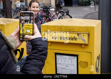 Frau macht mit ihrem Handy Fotos von einem Briefkasten nur für Liebesbriefe in der Stadt Köln, Deutschland. Frau fotografiert mit einem handlichen einen B. Stockfoto