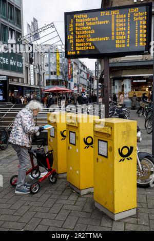 Eine ältere Frau mit Rollator wirft Briefe in einen Briefkasten in Neumarkt, Schildergasse, Köln. Eine Aeltere Frau mit Rollator wirft Brief Stockfoto