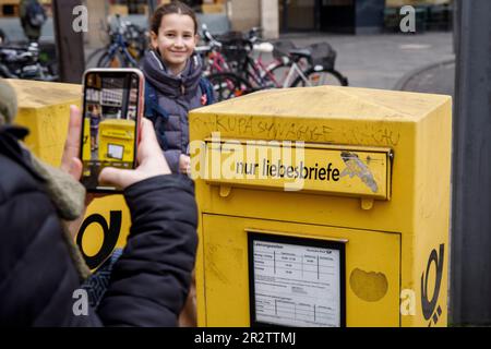 Frau macht mit ihrem Handy Fotos von einem Briefkasten nur für Liebesbriefe in der Stadt Köln, Deutschland. Frau fotografiert mit einem handlichen einen B. Stockfoto