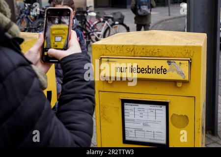 Frau macht mit ihrem Handy Fotos von einem Briefkasten nur für Liebesbriefe in der Stadt Köln, Deutschland. Frau fotografiert mit einem handlichen einen B. Stockfoto