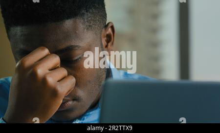 Müde erschöpfter Geschäftsmann afroamerikanischer kranker 30s Arbeiter Manager fühlt sich unwohl Kopfschmerzen Augenschmerzen nach Computerarbeit im Büro Müdigkeit Stockfoto