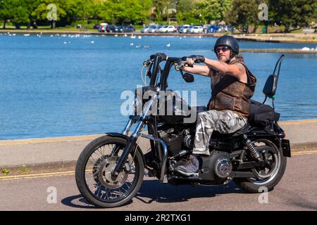 Poole, Dorset, Großbritannien. 21. Mai 2023 Bournemouth and Poole Distinguished Gentlemen’s Ride ist eine von vielen weltweit jährlich stattfindende Veranstaltung, um Geld und Bewusstsein für die Gesundheit von Männern zu schaffen. Im Rahmen der Fahrt fahren Hunderte von Motorrädern, viele davon im Vintage-Stil, durch den Poole Park auf dem Weg nach Bournemouth mit vielen ihrer Fahrer, die angemessen gekleidet sind, in Krawatten im Retro-Stil, Schnurrbart und Tweeds an einem schönen sonnigen Tag. Mann gekleidet in Lederjacke auf Harley Davidson Motorrad Motorrad Credit: Carolyn Jenkins/Alamy Live News Stockfoto