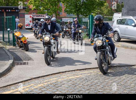 Warrington, Cheshire, Großbritannien. 21. Mai 2023. Großbritannien - die Distinguished Gentleman's Ride (DGR) vereint klassische und klassische Motorradfahrer aus der ganzen Welt, um Mittel und Bewusstsein für die Prostatakrebsforschung und die psychische Gesundheit von Männern zu sammeln. Eine Gruppe von Motorradfahrern aus ganz Warrington, gekleidet in ihren besten Anzügen und Krawatten, trafen sich bei ihrem Motorradhändler vor Ort und fuhren dann durch das Stadtzentrum, bevor es aus der Stadt und durch eine Kombination aus Dörfern und Städten ging. Sie landeten im Besucherzentrum der Jodrell Bank. Kredit: John Hopkins/Alamy Live News Stockfoto