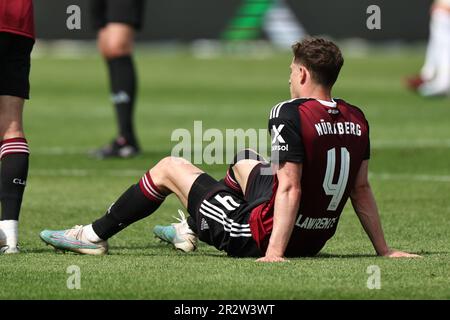 Nürnberg, Deutschland. 21. Mai 2023. Fußball: 2. Bundesliga, 1. FC Nürnberg - Hansa Rostock, 33. Spieltag im Max Morlock Stadion. Nürnbergs James Lawrence sitzt nach der letzten Pfeife auf dem Platz. Kredit: Daniel Karmann/dpa - WICHTIGER HINWEIS: Gemäß den Anforderungen der DFL Deutsche Fußball Liga und des DFB Deutscher Fußball-Bund ist es verboten, im Stadion aufgenommene Fotos und/oder das Spiel in Form von Sequenzbildern und/oder videoähnlichen Fotoserien zu verwenden oder verwenden zu lassen./dpa/Alamy Live News Stockfoto