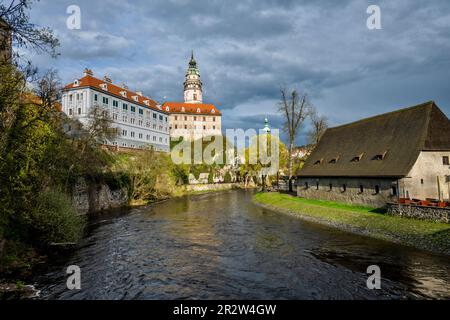 Schloss Cesky Krumlov auf einem felsigen Hügel am linken Ufer der Moldau und altes Korngebäude auf der rechten Seite. Tschechische republik. Stockfoto