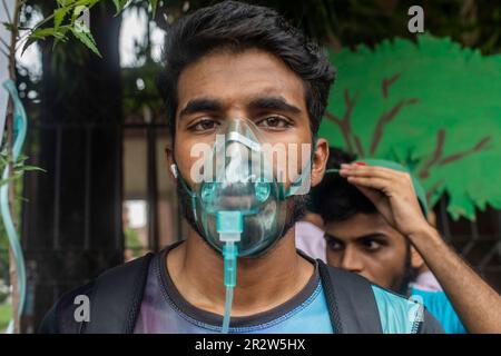 Dhaka, Bangladesch. 21. Mai 2023. An der Demonstration nimmt ein Protestteilnehmer mit Sauerstoffmaske Teil. Die Dhaka Metropolitan Police (DMP) hat Umweltaktivisten unter dem Banner von „Saat Masjid Sarak Gach Rakkha Andalan“ daran gehindert, Dhaka South City Corporation (DSCC) zu belagern und gegen das Fällen von Bäumen im Namen der Verschönerung der Saat Masjid Road von Dhanmondi zu protestieren. Kredit: SOPA Images Limited/Alamy Live News Stockfoto