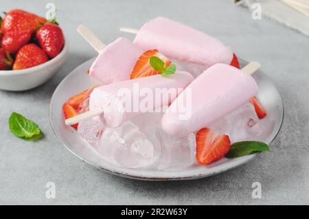Erfrischendes Erdbeereis, Ice Lolly mit frischer Erdbeere und Minze auf hellem Hintergrund, gesundes Dessert Stockfoto