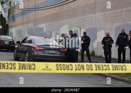 Paterson, Usa. 21. Mai 2023. Rettungsdienst und Polizisten überprüfen ein Fahrzeug am Tatort auf Beweise. Eine Person wurde am helllichten Tag an der Kreuzung East 29. Street und 18. Avenue erschossen. Das EMS erklärte den individuellen Tod am Tatort. Die Schießerei fand gegen 8:30 UHR Eastern Time statt. Von der Polizei von Paterson waren keine weiteren Informationen sofort verfügbar. Kredit: SOPA Images Limited/Alamy Live News Stockfoto