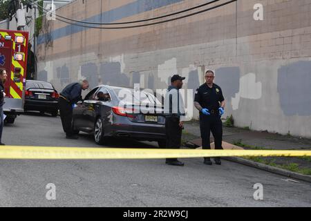 Paterson, Usa. 21. Mai 2023. Rettungsdienst und Polizisten überprüfen ein Fahrzeug am Tatort auf Beweise. Eine Person wurde am helllichten Tag an der Kreuzung East 29. Street und 18. Avenue erschossen. Das EMS erklärte den individuellen Tod am Tatort. Die Schießerei fand gegen 8:30 UHR Eastern Time statt. Von der Polizei von Paterson waren keine weiteren Informationen sofort verfügbar. Kredit: SOPA Images Limited/Alamy Live News Stockfoto