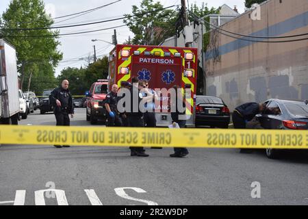 Paterson, Usa. 21. Mai 2023. Rettungsdienst und Polizisten am Tatort einer tödlichen Schießerei in Paterson. Eine Person wurde am helllichten Tag an der Kreuzung East 29. Street und 18. Avenue erschossen. Das EMS erklärte den individuellen Tod am Tatort. Die Schießerei fand gegen 8:30 UHR Eastern Time statt. Von der Polizei von Paterson waren keine weiteren Informationen sofort verfügbar. Kredit: SOPA Images Limited/Alamy Live News Stockfoto