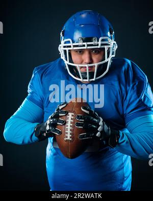 Porträt eines Mannes in blauer Uniform für american Football auf schwarzem Hintergrund. Stockfoto