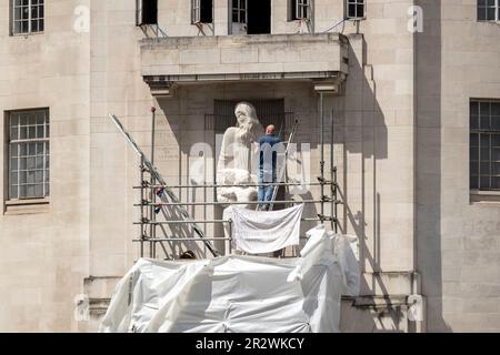 London, Großbritannien. 20. Mai 2023. Vor dem Broadcasting House sieht man einen Demonstranten, der das Eric Gills Prospero und die Ariel Statue hämmert. Ein Mann kletterte auf das Scaffolding Broadcasting House und zerstörte Eric Gills Prospero und Ariel Statue seit 4am Uhr morgens. Vor kurzem wurden Gerüste aufgestellt, die nach den Schäden, die während der Proteste im Januar entstanden sind, repariert werden sollten. (Foto: Hesther Ng/SOPA Images/Sipa USA) Guthaben: SIPA USA/Alamy Live News Stockfoto