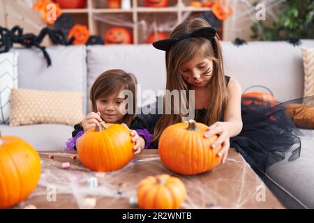 Bezaubernde Mädchen, die zu Hause eine halloween-Party veranstalten und Kürbis malen Stockfoto
