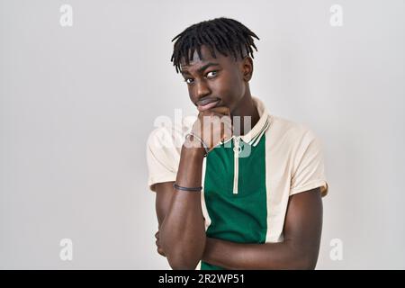 Afrikanischer Mann mit Dreadlocks, der über einem isolierten Hintergrund steht und über eine Frage besorgt denkt, besorgt und nervös mit der Hand am Kinn Stockfoto