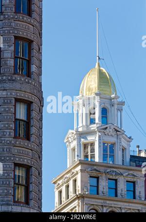 Zwei davon: Beaux Arts Wahrzeichen Flatiron Building und das benachbarte Sohmer Piano Company Building mit Goldkuppel passen gut zusammen. Stockfoto