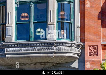 Eine Frau, die am Fenster eines Barnes & Noble Ladens im New Yorker Wahrzeichen Century Building gegenüber dem Union Square Park liest. Stockfoto