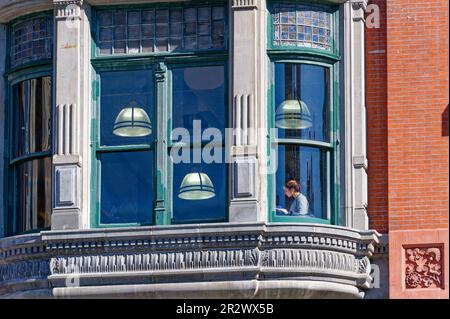 Eine Frau, die am Fenster eines Barnes & Noble Ladens im New Yorker Wahrzeichen Century Building gegenüber dem Union Square Park liest. Stockfoto