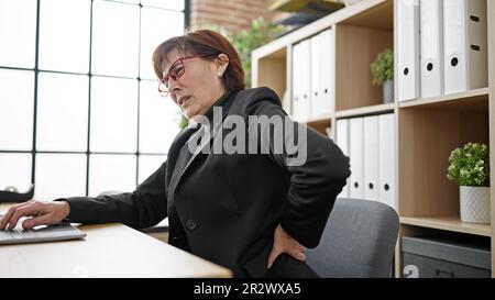 Reife hispanische Geschäftsfrau mit Rückenschmerzen im Büro Stockfoto