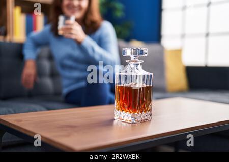 Frau mittleren Alters trinkt Lakerei sitzen auf dem Sofa zu Hause Stockfoto