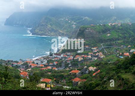 Atemberaubender Blick auf das Dorf Porto da Cruz auf Madeira, Portugal. Kleine Stadt in den Hügeln an der Küste des Atlantischen Ozeans. Dominanter Rock von Th Stockfoto