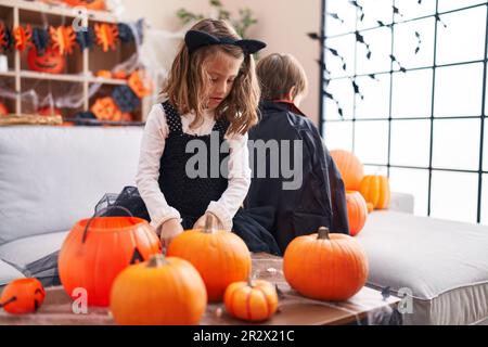 Ein bezaubernder Junge und ein bezauberndes Mädchen, die zu Hause halloween feiern Stockfoto