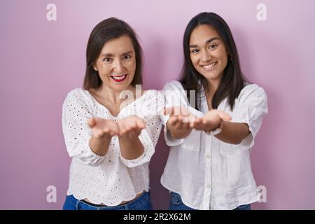 Lateinamerikanische Mutter und Tochter lächeln zusammen mit den Händen Hand zusammen, empfangen oder geben Gesten. Halt und Schutz Stockfoto