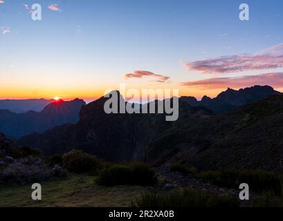 Der Sonnenaufgang in den Bergen von Madeira ist von Sonnenlicht umgeben und bietet einen malerischen Blick auf die Landschaft und den Pico Ruivo, Portugal. Stockfoto