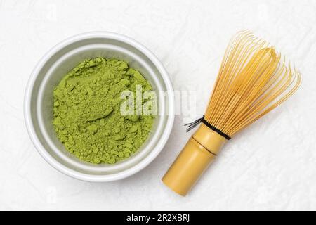 Grünes Matcha-Pulver in einer Schüssel. Chasen-Schneebesen für die Zubereitung von grünem Matcha-Tee. Flach verlegt. Weißer Hintergrund Stockfoto