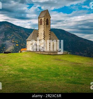 Berühmte Kirche St. Jakob ( San Giacomo) auf der grünen Wiese. Alte Kirche mit Bergkämmen im Hintergrund, in der Nähe des Dorfes Santa Maddalena in Funes val Stockfoto