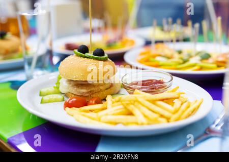 Mini-Burger und Bratkartoffeln mit Sauce auf weißem Teller. Kindermahlzeit Stockfoto