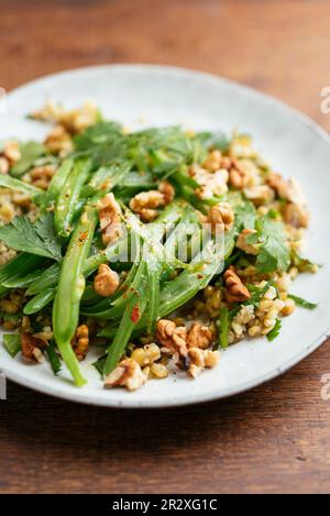 Teller mit hausgemachtem Freekeh mit grünen Bohnen und Kräutersalat. Stockfoto