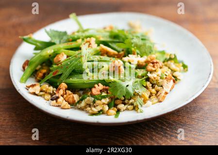 Teller mit hausgemachtem Freekeh mit grünen Bohnen und Kräutersalat. Stockfoto