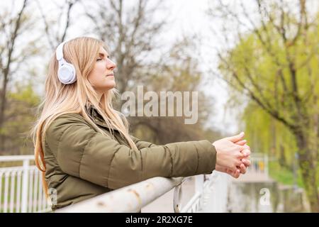 Entspannte Frau mit Kopfhörern, die frische Luft atmet und im Park Musik hört Stockfoto