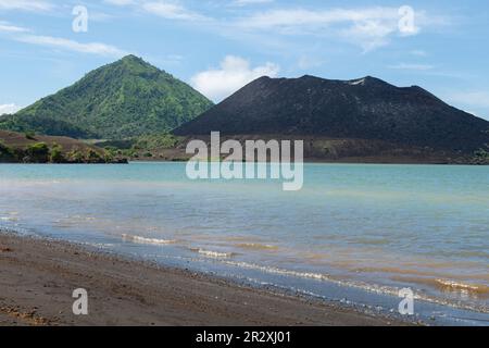 Papua-Neuguinea, New Britain Island, Rabaul, Hot Springs. Schwarzer Sandstrand mit Vulkan Mount Tavurvur in der Ferne. Stockfoto