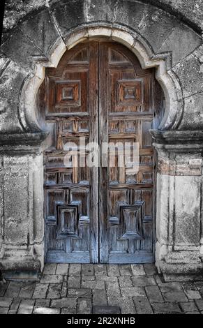 Diese altmodischen, handgefertigten Holztüren führen in eine historische Kapelle, die 1731 in der Mission Espada, südlich von San Antonio, Texas, USA, erbaut wurde. Stockfoto