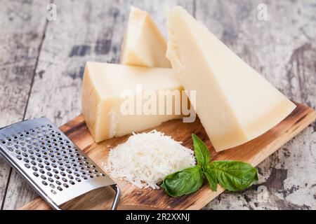 geriebener Parmesan-Käse und Metall-Reibe auf Holzbrett Stockfoto