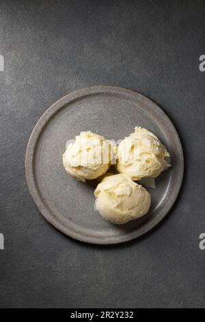 Drei Vanille-Eiskugeln auf grauem Teller, Draufsicht Stockfoto