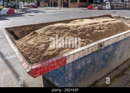 Ein Baucontainer, der auf der Straße voller Sand geparkt ist, um zu arbeiten Stockfoto