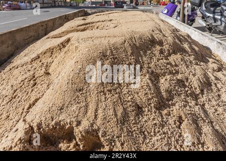 Ein Metallcontainer, der auf der Straße voller Sand geparkt ist, um auf einer nahegelegenen Baustelle zu arbeiten Stockfoto