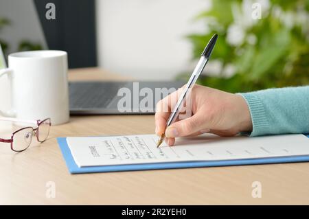 Nahaufnahme einer Frau, die das Formular auf einem Tisch ausfüllt Stockfoto