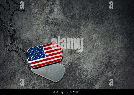 US-Hundemarken auf Steinhintergrund mit US-Flagge. Für Memorial Day, Veteran's Day oder andere patriotische amerikanische Veranstaltungen. Stockfoto