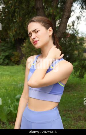 Junge Frau mit Nackenschmerzen im Freien Stockfoto