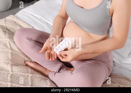 Schwangere Frau nimmt Pillen im Bett, Nahaufnahme Stockfoto