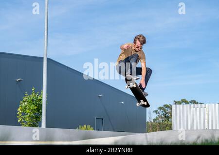 Skateboarder, der ollie-Trick in einer urbanen Szene macht. Stockfoto