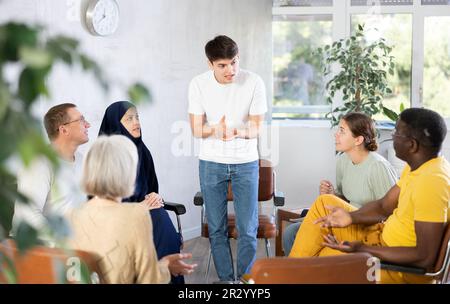 Emotionaler junger Mann, der mit Kollegen im Büro-Wohnzimmer spricht Stockfoto