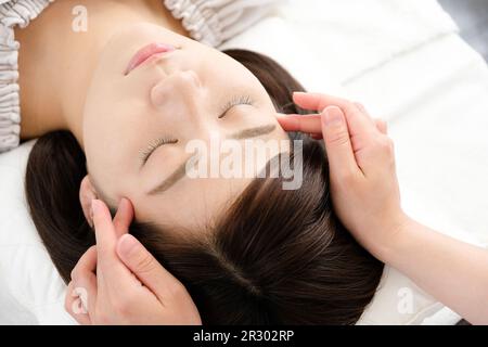 Eine Frau, die Temple Shiatsu bei Akupunktur empfängt Stockfoto