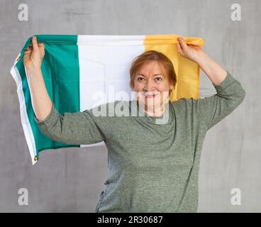 Fröhliche Seniorin mit irischer Flagge Stockfoto
