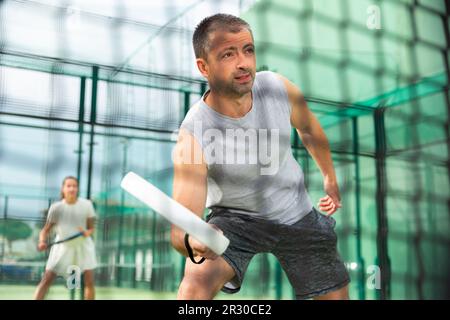 Junger erwachsener Mann, der im Freien Paddeltennis spielt Stockfoto