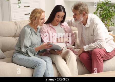 Glückliche schwangere Frau, die Zeit mit ihren Eltern zu Hause verbringt. Die Reaktion der Großeltern auf den zukünftigen Enkel Stockfoto